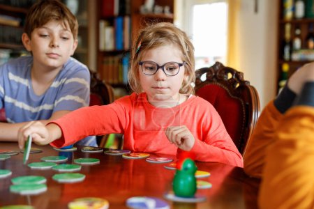 Photo for Family playing board game at home. Kids play strategic game. Little sister girl and two school brothers boys. Fun indoor activity. Siblings bond. Educational toys - Royalty Free Image