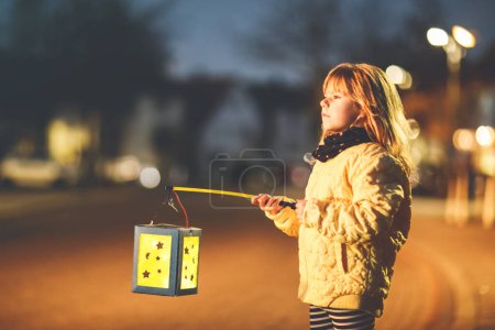Photo for Little preschool kid girl holding selfmade traditional lanterns with candle for St. Martin procession. child happy about children and family parade in kindergarten. German tradition Martinsumzug. - Royalty Free Image