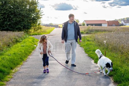 Photo for Father, little preschool girl and family dog walking outdoors. Middle-aged man and cute daughter with pet. Happy child and dad together, having fun - Royalty Free Image