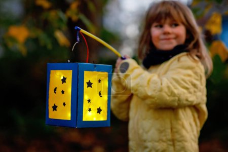 Photo for Closeup of little preschool kid girl holding selfmade traditional lanterns with candle for St. Martin procession. child happy about family parade in kindergarten. German tradition Martinsumzug. - Royalty Free Image