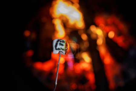 Photo for Marshmallows with Halloween pictures over fire. Funny leisure on traditional spooky holiday for children and families - Royalty Free Image