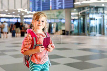 Photo for Little preschool girl at airport terminal. Happy child going on vacations by airplane. Smiling kid with passport and bag - Royalty Free Image
