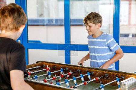 Photo for Two smiling school boys playing table soccer. Happy excited children having fun with family game with siblings or friends. Positive preteen kids or teenager - Royalty Free Image