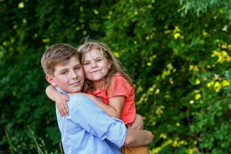 Photo for Happy Little Girl Embraces Her Loving Brother, Teenager Boy, Showcasing the Warmth and Love within Their Family Bond. Carefree Childhood, Brother and Sister Bonding - Royalty Free Image