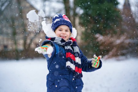 Foto de Linda niña preescolar al aire libre en el parque de invierno. Adorable niño feliz saludable jugando y divirtiéndose con la nieve, al aire libre en el día frío. Ocio activo con niños en invierno. - Imagen libre de derechos