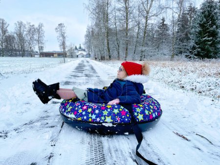 Photo for Active prechool girl sliding down the hill on snow tube. Cute little happy child having fun outdoors in winter on sledge . Healthy excited kid tubing snowy downhill, family winter time - Royalty Free Image