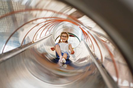 Photo for Little preschool girl riding from childrens slides on playground. Happy smiling child having fun in game center for kids - Royalty Free Image