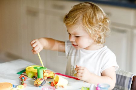 Photo for Adorable cute little toddler girl with colorful clay. Healthy baby playing and creating toys from play dough. Small kid molding modeling clay and learning. - Royalty Free Image