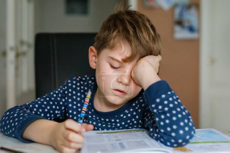 Fleißiger, trauriger Schuljunge, der Hausaufgaben macht. Verärgertes müdes Kind auf dem Heimweg zur Schule, lernen