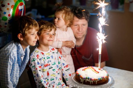 Téléchargez les photos : Adorable happy little kid boy celebrating his birthday. Child blowing candles on cake. Father, brother and baby sister sitting together. Happy family - en image libre de droit