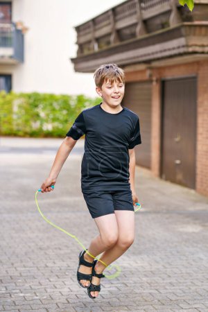 Foto de Niño guapo con saltar la cuerda al aire libre. Adolescente niño saltando y entrenamiento en el campamento deportivo - Imagen libre de derechos