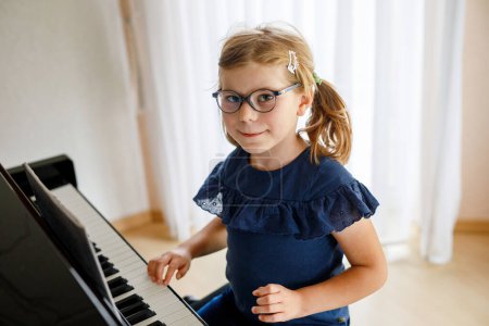 Téléchargez les photos : Belle petite fille de maternelle jouant du piano à l'école de musique. Enfant mignon s'amuser avec apprendre à jouer de l'instrument de musique. Éducation musicale précoce pour les enfants. - en image libre de droit