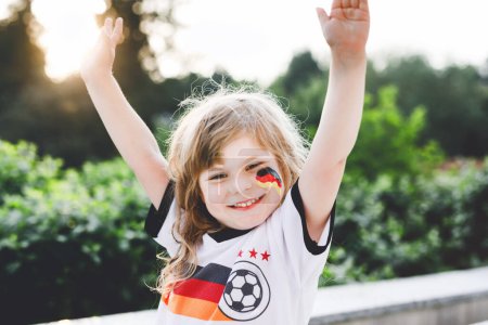 Photo for Little blond preschool girl watching soccer football cup game on public viewing. Happy joyful excited child about winning game match of favorite national football team. girl with German flag on face - Royalty Free Image