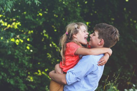 Photo for Happy Little Girl Embraces Her Loving Brother, Teenager Boy, Showcasing the Warmth and Love within Their Family Bond. Carefree Childhood, Brother and Sister Bonding - Royalty Free Image