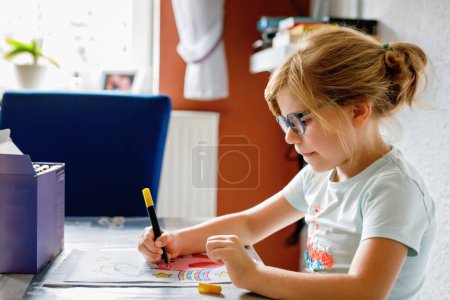 Téléchargez les photos : Mignon petit enfant d'âge préscolaire dessin à la maison. Fille heureuse avec des stylos en feutre coloré. Hobby pour les enfants. Activité de loisirs pour les jeunes enfants à l'école - en image libre de droit