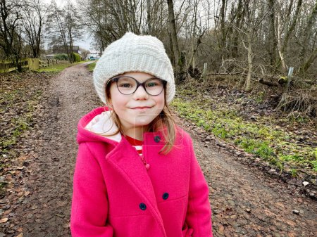 Photo for Portrait of a cute school girl with eyeglasses outdoors in park. Happy funny child on autumn, spring or winter day - Royalty Free Image