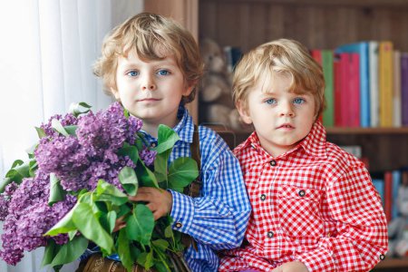 Foto de Dos niños adorables con flores para mamá en el Día de las Madres. Hermanos felices, lindo retrato de niños - Imagen libre de derechos