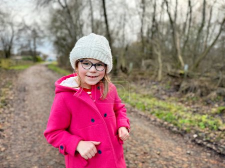 Téléchargez les photos : Portrait d'une jolie écolière avec des lunettes à l'extérieur dans le parc. Heureux enfant drôle à l'automne, au printemps ou en hiver - en image libre de droit