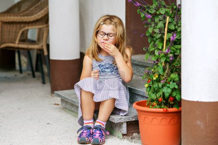 Téléchargez les photos : Jolie petite fille tenant des tomates en pot. Enfant d'âge préscolaire cueillette de légumes mûrs et manger des tomates. - en image libre de droit