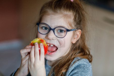 Foto de Una colegiala comiendo una manzana para el almuerzo escolar. Hansdsome chica almorzando. Alimento saludable para niños - Imagen libre de derechos