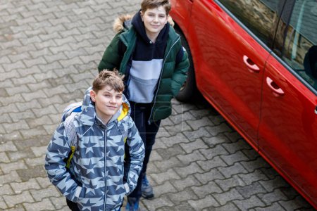 Photo for Two happy school students walking on street after school and chatting. Teenager boys, brothers and friends. Portrait of joyful young boys pupils with backpacks in good mood speaking outdoors in city - Royalty Free Image