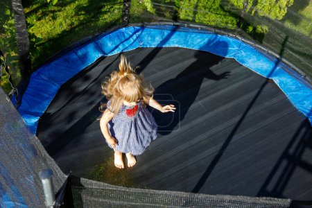 Photo for Little preschool girl jumping on trampoline. Happy funny toddler child having fun with outdor activity in summer. Sports and exercises for children. - Royalty Free Image