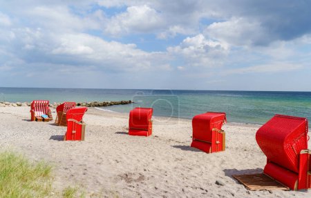 Fauteuils de plage traditionnels en osier sur la plage de la mer Baltique. Plage avec chaises rouges par une journée ensoleillée orageuse. Ostsee