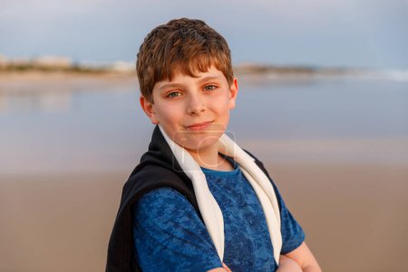 Photo for Happy cheerful teenager standing on beach at sunset. happy preteen boy smiling at the camera. Kid on family vacation at the sea - Royalty Free Image