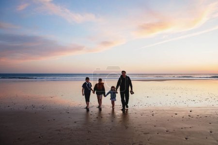 Photo for Portrait silhouettes of three children and dad happy kids with father on beach at sunset. happy family, Man, two school boys and one little preschool girl. Siblings having fun together. Bonding. - Royalty Free Image