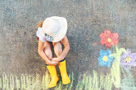 Photo for Cute little girl and flowers painted with colorful chalks on asphalt. Happy preschool child having fun with painting chalk picture. Creative leisure for children, drawing and painting - Royalty Free Image