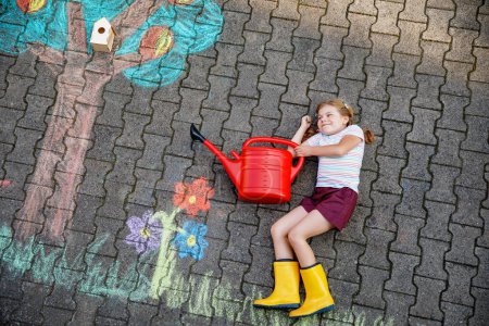 Photo for Cute little girl painting with colorful chalks apples harvest from apple tree on asphalt. Cute preschool child with having fun with chalk picture. Creative leisure for children, drawing and painting - Royalty Free Image