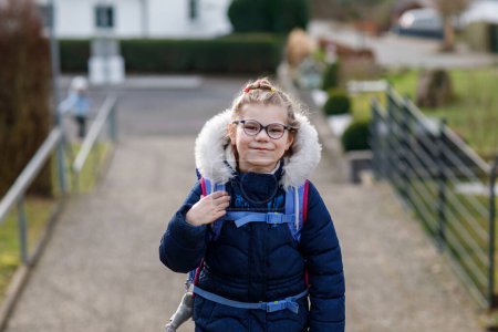 Photo for Cute little girl o the way to school. Healthy happy child with eyeglasses walking to primary school. Smiling child with schoolbag on the city street, outdoors. Back to school - Royalty Free Image