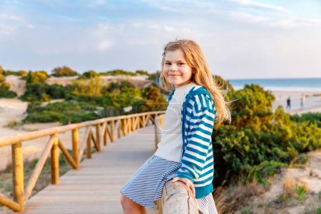 Photo for Adorable happy smiling little girl on beach vacation at sunset. Handsome cute preschool child with long blond hairs having fun on family vacations - Royalty Free Image