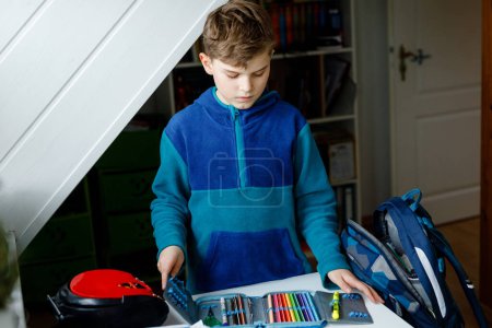 Photo for School kid boy getting ready in the morning for school. Healthy child filling satchel with books, pens, folders and school stuff. Preaparation, routine concept - Royalty Free Image