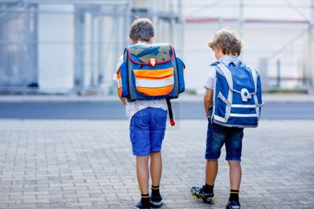Photo for Two little kid boys with backpack or satchel. Schoolkids on the way to school. Healthy adorable children, brothers and best friends outdoors on the street leaving home. Back to school. Happy siblings - Royalty Free Image