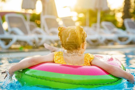 Photo for Happy little girl with inflatable toy ring float in swimming pool. Little preschool child learning to swim and dive in outdoor pool of hotel resort. Healthy sport activity and fun for children - Royalty Free Image