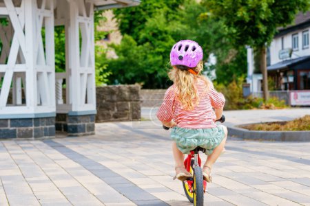 Photo for Little preschool girl with helmet running with balance bike on summer day. Happy child driving, biking with bicycle, outdoor activity. Happiness, childhood. Summer activity for children - Royalty Free Image