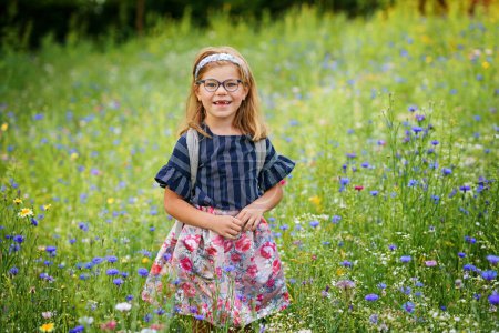 Niña preescolar en el campo con flores diferentes. Feliz niño recogiendo flor con diferentes colores. Verano, Infancia, Felicidad, Concepto Familiar