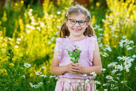 Happy toddler girl holding a bouquet of wildflowers