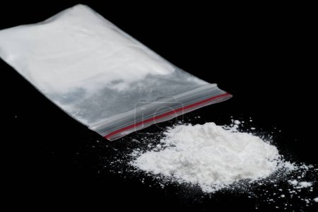 Cocaine or other illegal drugs, white powder, syringe, isolated on black glossy background