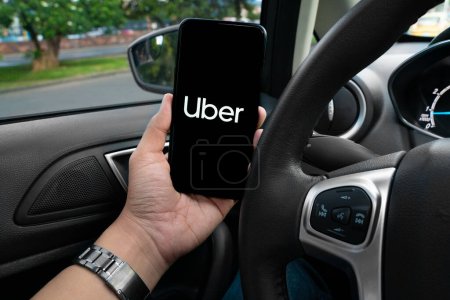 Téléchargez les photos : Chauffeur Uber tenant smartphone dans la voiture. Uber est une société américaine offrant des services de transport en ligne. Uber APP - en image libre de droit