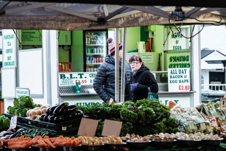 Téléchargez les photos : Epsom, Surrey, Londres Royaume-Uni, 19 novembre 2022, Femme du Moyen Âge marchant au-delà d'un étal de fruits et légumes du marché - en image libre de droit