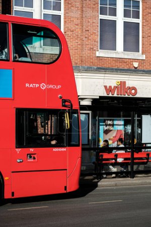 Foto de Epsom, Surrey, Londres Reino Unido, 19 de febrero de 2023, Red Double Decker Bus Fuera de una tienda de descuentos de High Street Wlko con gente esperando en la parada de autobús - Imagen libre de derechos
