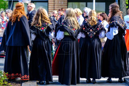Téléchargez les photos : Sandnes, Norvège, 17 mai 2023, Quatre femmes en robe traditionnelle regardant le défilé de la fête de l'indépendance Sandnes Norvège avec des sacs à l'appareil photo - en image libre de droit