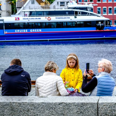 Foto de Stavanger, Rogaland, Noruega, 19 de mayo de 2023, una mujer mayor o una abuela tomando fotos de un niño o una nieta salida de la familia Stavanger Harbour con un ferry en el fondo - Imagen libre de derechos