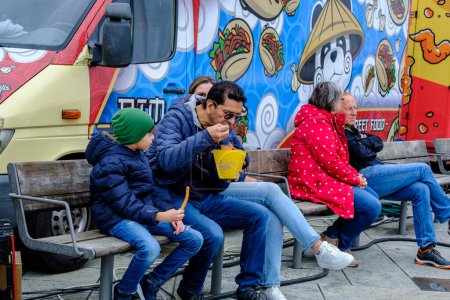 Téléchargez les photos : Stavanger, Rogaland, Norvège, 19 mai 2023, La famille père et fils assis à l'extérieur sur un banc au Pop-up Food Market Centre-ville Stavanger - en image libre de droit
