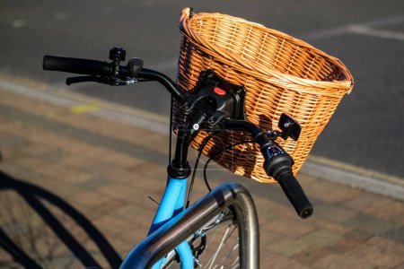 Téléchargez les photos : Epsom Surrey, Royaume-Uni, 30 mars 2024, Staitionenry Blue Bicycle avec un panier d'achat en osier attaché au guidon sans personne - en image libre de droit