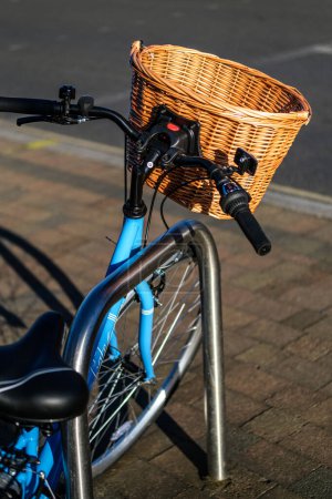 Téléchargez les photos : Epsom Surrey, Royaume-Uni, 30 mars 2024, Staitionenry Blue Bicycle avec un panier d'achat en osier attaché au guidon sans personne - en image libre de droit