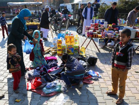 Téléchargez les photos : OVAKENT,HATAY,TURKEY-DECEMBER 10:Unidentified  Afghan Woman buying Clothes at  Farmers Market. December 10,2016 in Ovakent, Hatay, Turkey - en image libre de droit