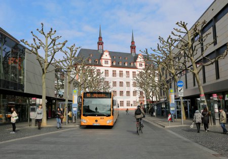 Foto de MAINZ, ALEMANIA-MARZO 28: Autobús público naranja y personas no identificadas caminando por la calle. 28 de marzo de 2015 en Mainz, Alemania - Imagen libre de derechos